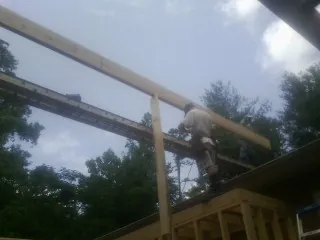 Carpenter setting a ridge beam over a new addition frame — Ice Dam Removal by Roofing Brothers in Bentonville
