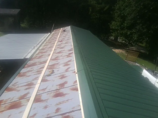 Old rusted panels beside newly installed green metal roofing — Wind Damage Roof Repair by Roofing Brothers in Bentonville