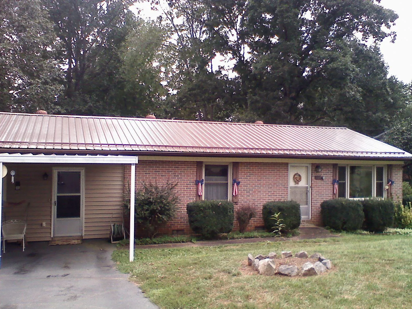 Bronze metal roof and carport on a brick ranch home — Roof Repair work by our crew in Bentonville